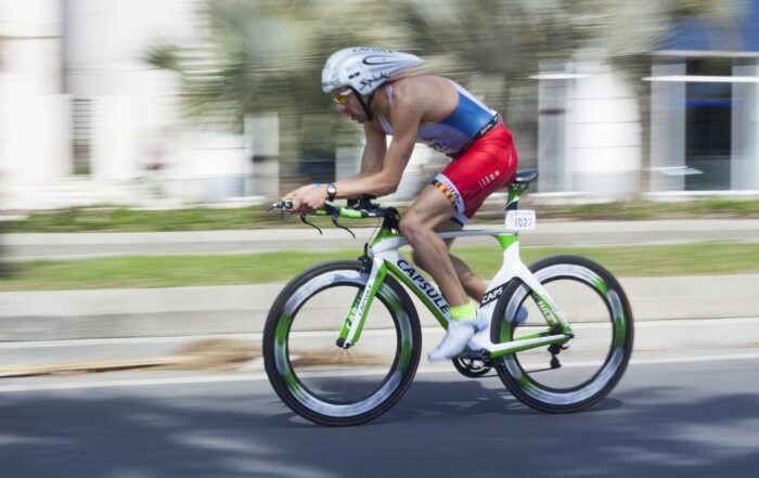 cyclist moving at top-speed, soccer players warming up, tennis player lying down in exhaustion, person picking up a barbell, two women practicing box jumps, man sprinting with a weighted sled