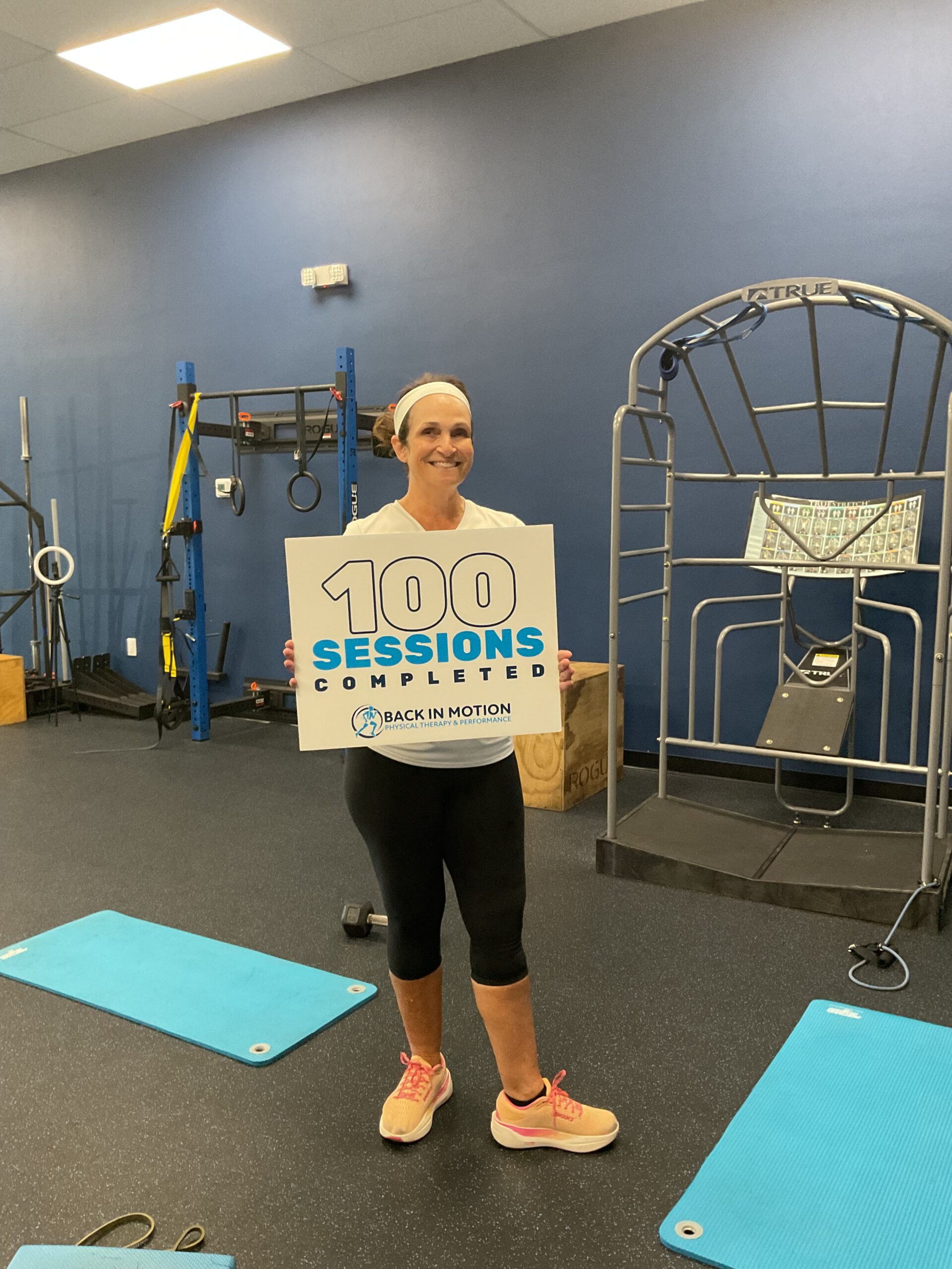 Client holding a 100 Sessions Completed sign